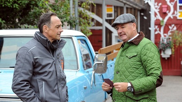 Dahoam is Dahoam: Mike (Harry Blank, links) überreicht Hubert (Bernhard Ulrich, rechts) die Opernkarten.  | Bild: BR/Marco Orlando Pichler