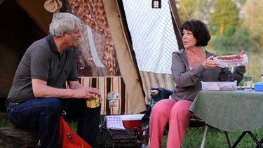 Joseph macht sich über Rosis Survival-Ausrüstung beim Zelten lustig. Von links: Joseph (Wilhelm Manske) und Rosi Brunner (Brigitte Walbrun). | Bild: BR/Marco Orlando Pichler