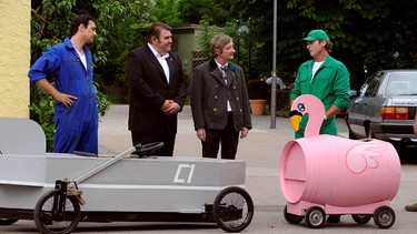 Mike und Sebastian wollen sich gegenseitig mit ihren selbst gebauten Seifenkisten übertrumpfen. Von links: Mike Preissinger (Harry Blank), Pfarrer Neuner (Peter Rappenglück), Xaver (Michael Schreiner) und Sebastian Wildner (Herbert Ulrich). | Bild: BR/Marco Orlando Pichler