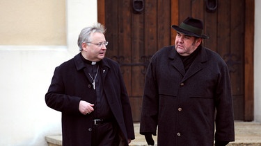 Der Bischof erteilt Pfarrer Neuner eine sanfte Rüge wegen des Anrufbeantworters. Von links: Bischof (Helmut W. Brossmann) und Pfarrer Neuner (Peter Rappenglück). | Bild: BR/Marco Orlando Pichler