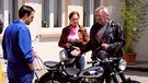 Trixi und Martin werden von Mike beim Üben mit dem Motorrad erwischt. Von links: Mike (Harry Blank), Trixi Preissinger (Doreen Dietel) und Martin Kirchleitner (Hermann Giefer). | Bild: BR/Marco Orlando Pichler