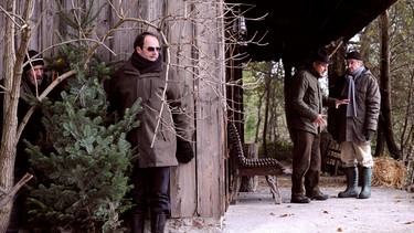 Martin und Hubert verstecken sich mit ihrem gestohlenen Christbaum vor Schattenhofer. Von links: Martin (Hermann Giefer), Hubert Kirchleitner (Bernhard Ulrich), Bürgermeister Schattenhofer (Werner Rom) und Xaver (Michael Schreiner). | Bild: BR/Marco Orlando Pichler