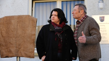 Alois ist sauer, dass Monika das Schild verdeckte, um auf dem Behindertenparkplatz zu parken. Von links: Monika Vogl (Christine Reimer) und Alois Preissinger (Erich Hallhuber sen.). | Bild: BR/Marco Orlando Pichler