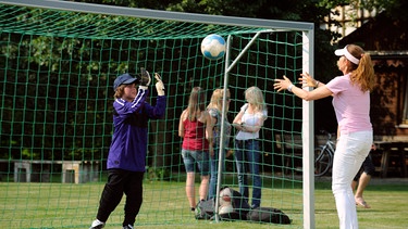 Trixi unterstützt Christian beim Aufwärmen für das anstehende Fußballspiel. Von links: Christian (Marinus Kaffl) und Trixi Preissinger (Doreen Dietel, rechts). | Bild: BR/Marco Orlando Pichler