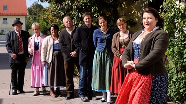 Die Lansinger ahnen nicht, worauf sie sich bei der Doku einlassen. Von links: Ludwig (Martin Wenzl), Annalena (Heidrun Gärtner), Veronika Brunner (Senta Auth) und Monika Vogl (Christine Reimer). | Bild: BR/Marco Orlando Pichler