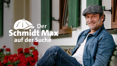 Sendereihenbild "Der Schmidt Max auf der Suche": Schmidt Max sitzt vor einem Haus auf einer Bank, neben ihm Geranien | Bild: BR/Schelke Bonnetsmüller