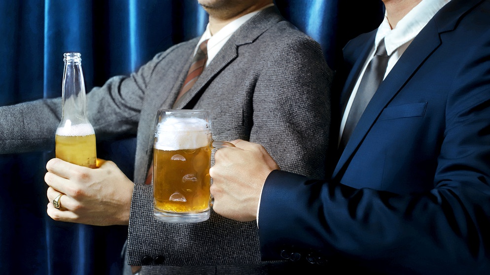 Zwei Männer in Anzug und Krawatte halten Bierflasche bzw. gefüllten -krug in Händen. | Bild: BR/ Monika Rasciute, Hannah Wiesner