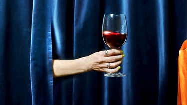 Ein Glas Rotwein wird von einer Frauenhand durch einen blauen Vorhang gereicht. | Bild: BR/ Monika Rasciute, Hannah Wiesner