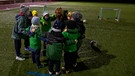 Die ehrenamtliche Trainerin steht gemeinsam mit ihrem Fußballteam im Kreis beim Training. | Bild: BR