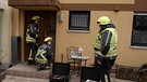 Feuerwehrleute brechen eine Haustür auf. | Bild: BR