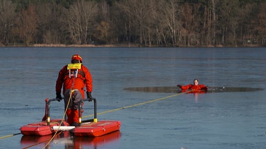 Mann von der DLRG rettet seinen Kollegen aus dem Wasser. | Bild: BR