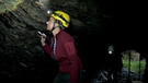 Frau mit Stirnlampe in einer Höhle. | Bild: BR