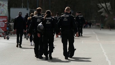 Polizisten laufen auf einer Straße. | Bild: BR