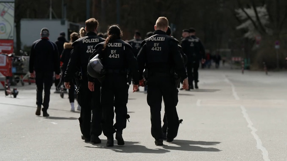 Polizisten laufen auf einer Straße. | Bild: BR