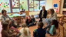 Kinder und Betreuerinnen sitzen gemeinsam in der Kinderkonferenz. | Bild: BR