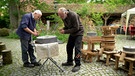 Wolfgang Strakosch und Thomas Schmiedeke arbeiten an einem Mühlstein. | Bild: BR