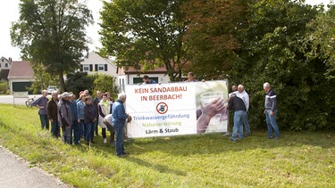 Die Bürger demonstrieren gegen den Quarzsandabbau in Beerbach mit einem Plakat. | Bild: BR