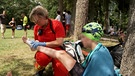 Eine Ehrenamtliche  der DLRG versorgt eine verletzte Triathletin. | Bild: BR