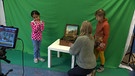 Kinder eines Kindergartens in Herzogenaurach stehen vor einem Greenscreen und lernen, wie man filmt. | Bild: BR