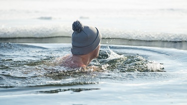 Mann badet im Winter im See.  | Bild: stock.adobe.com/Suzi Media