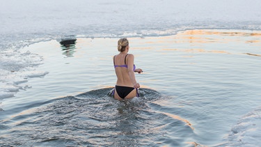 Frau badet im Winter im See.  | Bild: stock.adobe.com/Hanna