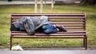 Ein obdachloser Mann schläft auf einer Parkbank.  | Bild: picture alliance / Zoonar | Cylonphoto