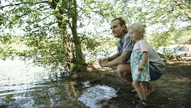 Junger Vater mit seiner Tochter am See.  | Bild: BR