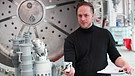 Stefan Brieschenk, technischer Leiter des Start-up-Unternehmens "Rocketfactory Ausburg" hält ein Gelenk aus der Automobilindustrie in der Hand. Junge Raumfahrtfirmen suchen nach neuen Konzepten, auch bei anderen Branchen, um Raketen kostengünstiger zu produzieren.  | Bild: BR/Gut zu wissen