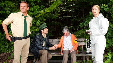 Dr. Anja Licht (Karin Thaler, rechts) macht Hubert (Christian Tramitz, links.) und Staller (Helmfried von Lüttichau, 2. von links) darauf aufmerksam, dass die Tote (Irene Richter), die sie auf der Parkbank entdeckt haben, blind war. Der Schwerbehindertenausweis lässt daran keinen Zweifel. | Bild: ARD/TMG/Chris Hirschhäuser