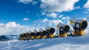 Viele Schneekanonen stehen hintereinander neben der Skipiste im Zillertal. | Bild: picture alliance / imageBROKER | Moritz Wolf