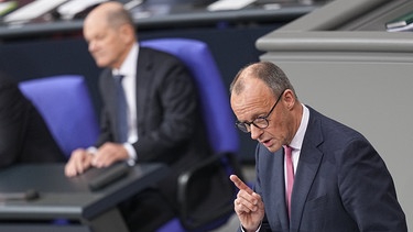 Bundeskanzler Olaf Scholz (SPD) hört Friedrich Merz (r), CDU Bundesvorsitzender und CDU/CSU Fraktionsvorsitzender im Bundestag, zu, als dieser bei der Debatte um das Zustrombegrenzungsgesetz im Plenarsaal im Bundestag spricht. | Bild: picture alliance/dpa | Michael Kappeler