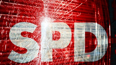 Logo der Partei SPD - Sozialdemokratische Partei Deutschland in Scherben vor zerbrochener / zerschlagener Fensterscheibe. Symbolbild | Bild: picture alliance / CHROMORANGE | Michael Bihlmayer