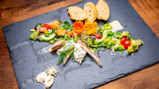 Der Gruß aus der Küche von Barbara Friedmann: Sommerlicher Salat mit Forellen-, Radieschencremenocken und Bierbaguette. | Bild: BR/megaherz GmbH/Moritz Sonntag