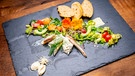 Der Gruß aus der Küche von Barbara Friedmann: Sommerlicher Salat mit Forellen-, Radieschencremenocken und Bierbaguette. | Bild: BR/megaherz GmbH/Moritz Sonntag