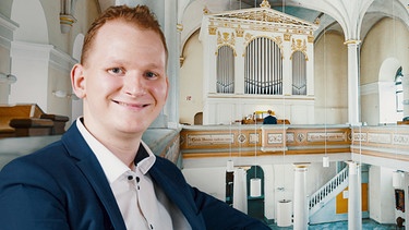 Christoph sitzt vor einer Orgel in einer Kirche. | Bild: BR