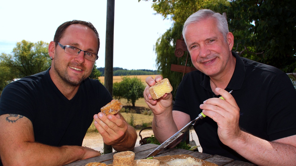 Alexander Herrmann (rechts) und Markus Berl mit Reibe-Camembert am Tisch. | Bild: BR/Frank Johne