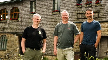 Von links: Der Vorstand des Fichtelgebirgsverein Stefan mit Lukas, dem Pächter der Kösseine im Fichtelgebirge und dem Moderator Marcus Fahn. | Bild: BR/Watch Lola GmbH/Matthias Schwinn