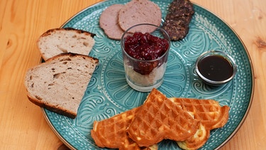 Der Gruß aus der Küche von Rahel Kremershof aus dem Bergischen Land: Bergische Kaffeetafel mit Waffeln, Milchreis mit Kirschen, Holzofenbrot, Leberwurst, Rindsalami, Zuckerrübensirup. | Bild: WDR/BR/megaherz gmbh/Melanie Grande