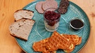 Der Gruß aus der Küche von Rahel Kremershof aus dem Bergischen Land: Bergische Kaffeetafel mit Waffeln, Milchreis mit Kirschen, Holzofenbrot, Leberwurst, Rindsalami, Zuckerrübensirup. | Bild: WDR/BR/megaherz gmbh/Melanie Grande