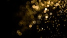 Ein goldenes Bokeh aus Wassertropfen auf einem schwarzen Hintergrund. | Bild: stock.adobe.com/pandaclub23