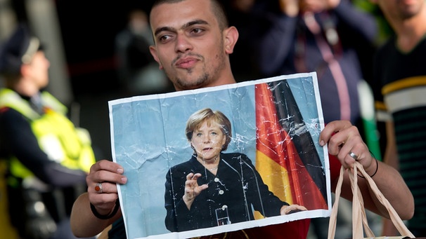 Flüchtling mit Merkel-Plakat | Bild: picture-alliance/dpa