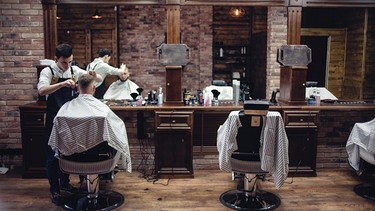 Ein Mann bekommt in einem Barbershop die Haare geschnitten.  | Bild: stock.adobe.com/liyasov