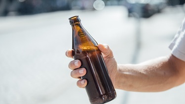 Eine Person hält eine Flasche Bier in der Hand. | Bild: BR/Johanna Schlüter