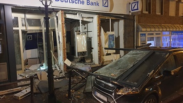 ARCHIV - 17.03.2021, Nordrhein-Westfalen, Mönchengladbach: Ein stark beschädigtes Auto steht vor einer Bankfiliale, die durch eine Geldautomatensprengung verwüstet ist. Unbekannte hatten den Geldautomaten gesprengt. Anschließend flüchteten sie in einem dunklen Auto, wie die Polizei mitteilte. (Zu dpa: «Sprengattacken von Geldautomaten-Bombern mehr als verdoppelt») Foto: Theo Titz/dpa - ACHTUNG: Kennzeichen wurde aus rechtlichen Gründen gepixelt +++ dpa-Bildfunk +++ | Bild: dpa-Bildfunk/Theo Titz