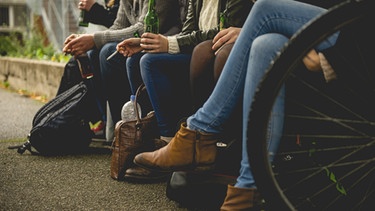 Jugendliche sitzen draußen zusammen, rauchen und trinken zusammen. | Bild: stock.adobe.com/Stephan Böhm