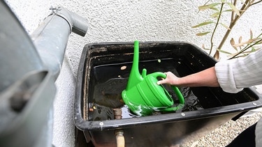 Frau schöpft Gieswasser | Bild: Picture alliane/dpa