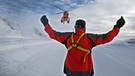 Ein Bergwachtsanwärter weist einen Rettungshubschrauber auf seinem Landeplatz neben der Skipiste ein. | Bild: picture alliance / dpa | Karl-Josef Hildenbrand