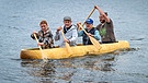 Von links: Lea Braun, Sebastian Bezzel, Simon Schwarz und Thomas Hauke paddeln in einem Einbaum. | Bild: BR/Film Five GmbH/Ralf Wilschewski