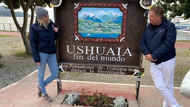 Ushuaia in Argentinien. Die Reiseleiter Caro Sattler und Konstantin Patschke machen vor ihrer Wanderung noch ein Foto vor dem Schild "Fin del Mundo". | Bild: BR/Bewegte Zeiten Filmproduktion GmbH/Gerrit Mannes