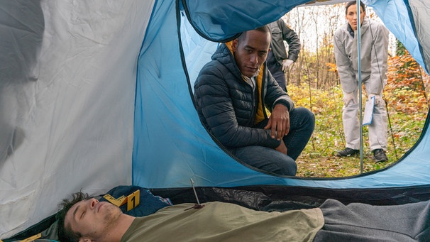 Jerry Paulsen (Peter Marton, hinten links) und Sonja Bitterling (Genoveva Mayer, hinten rechts) untersuchen die Leiche (Luca Garnreiter, vorne) und den Tatort. | Bild: ARD/Lucky Bird Pictures/Angela M. Schlabitz